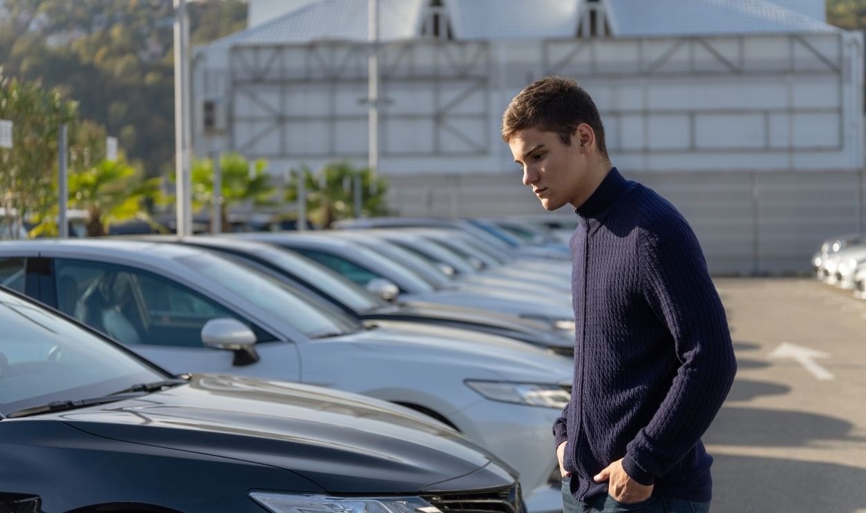 Young handsome man choosing a car in a car showroom