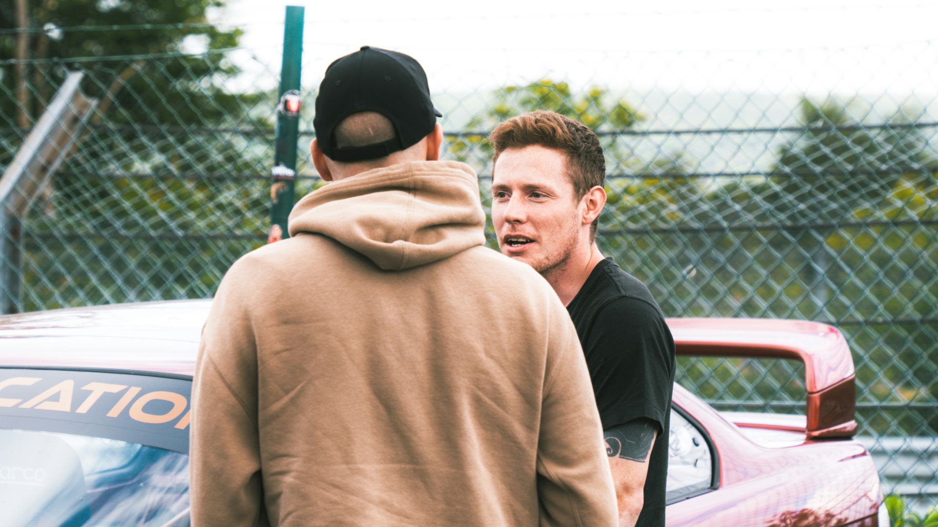 A group of men standing next to each other in front of a car