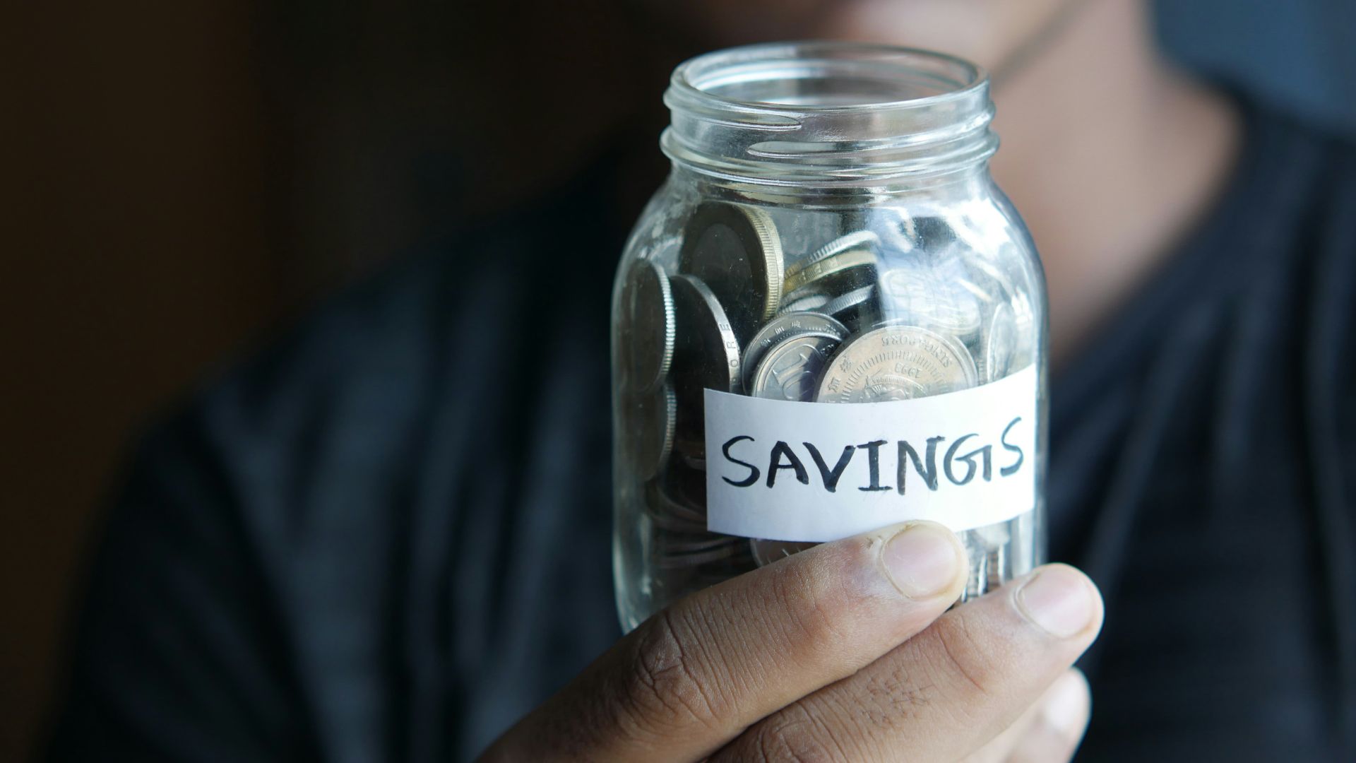 a man holding a jar with a savings label on it