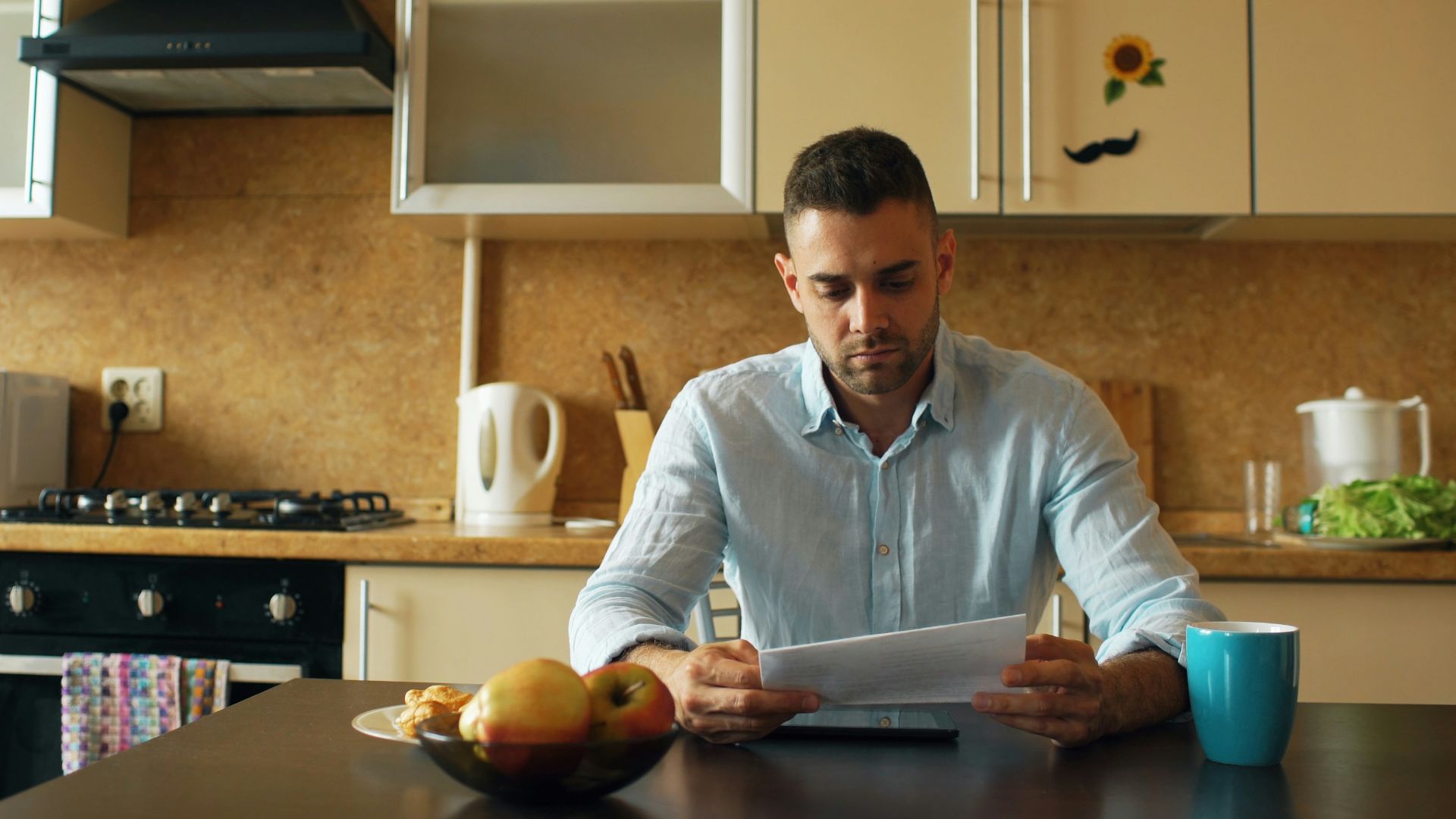 Man reading document at kitchen table with coffee