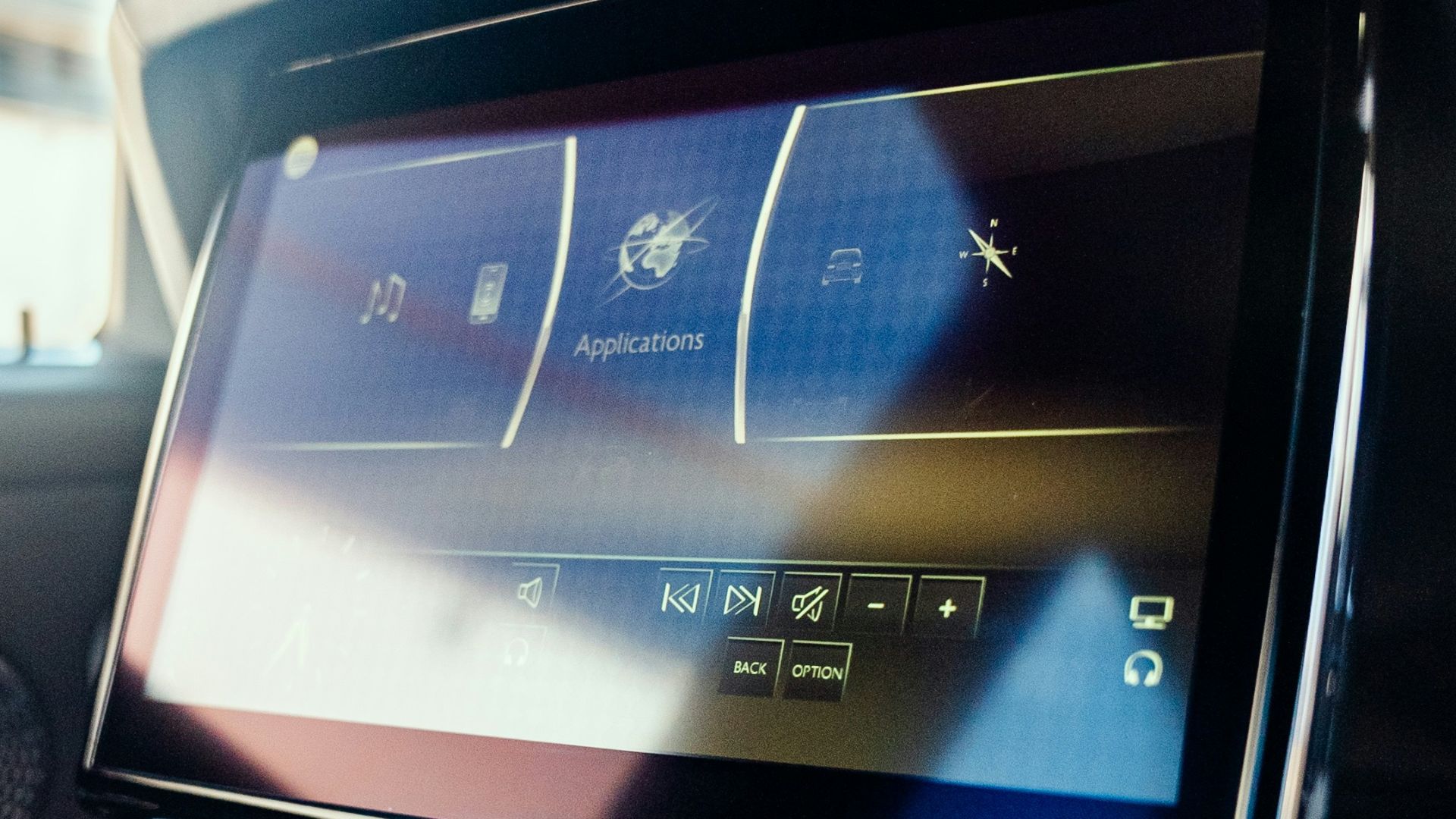 An interior car screen displays applications
