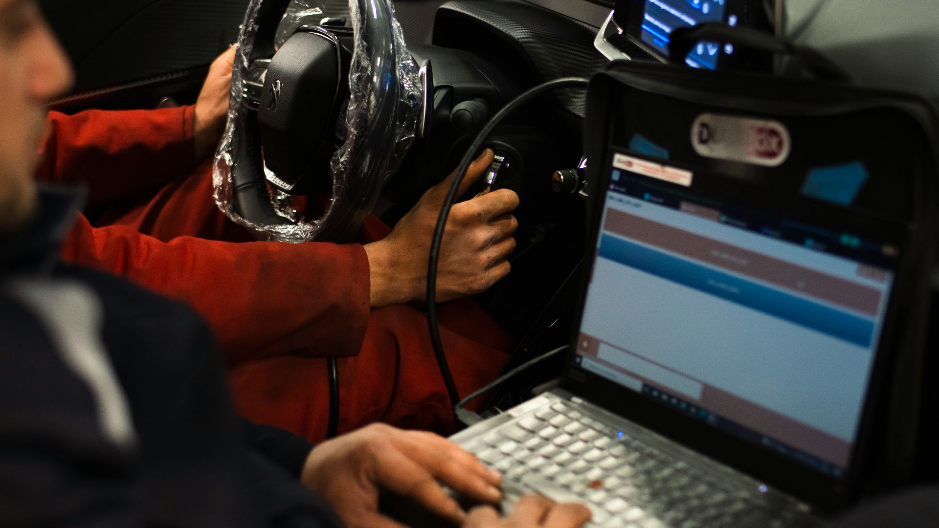 A man sitting in a car using a laptop computer