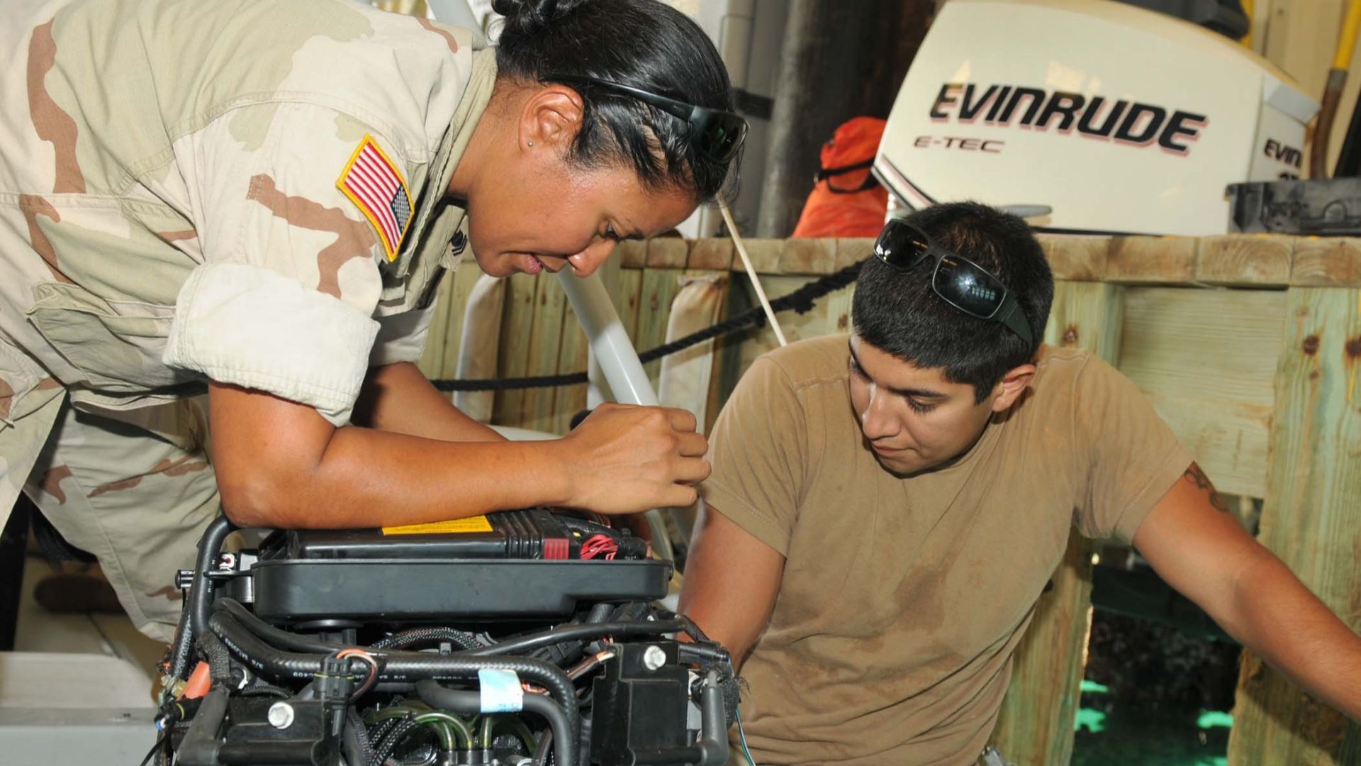 Coast Guard Petty Officer 2nd Class Roxanne L. Guerrero (left) and Coast Guard Machinery Technician 3rd Class Milo A. Serrano (right), deployed to Joint Task Force Guantanamo with Maritime Safety and Security Team 91103, repair an outboard motor on a patr