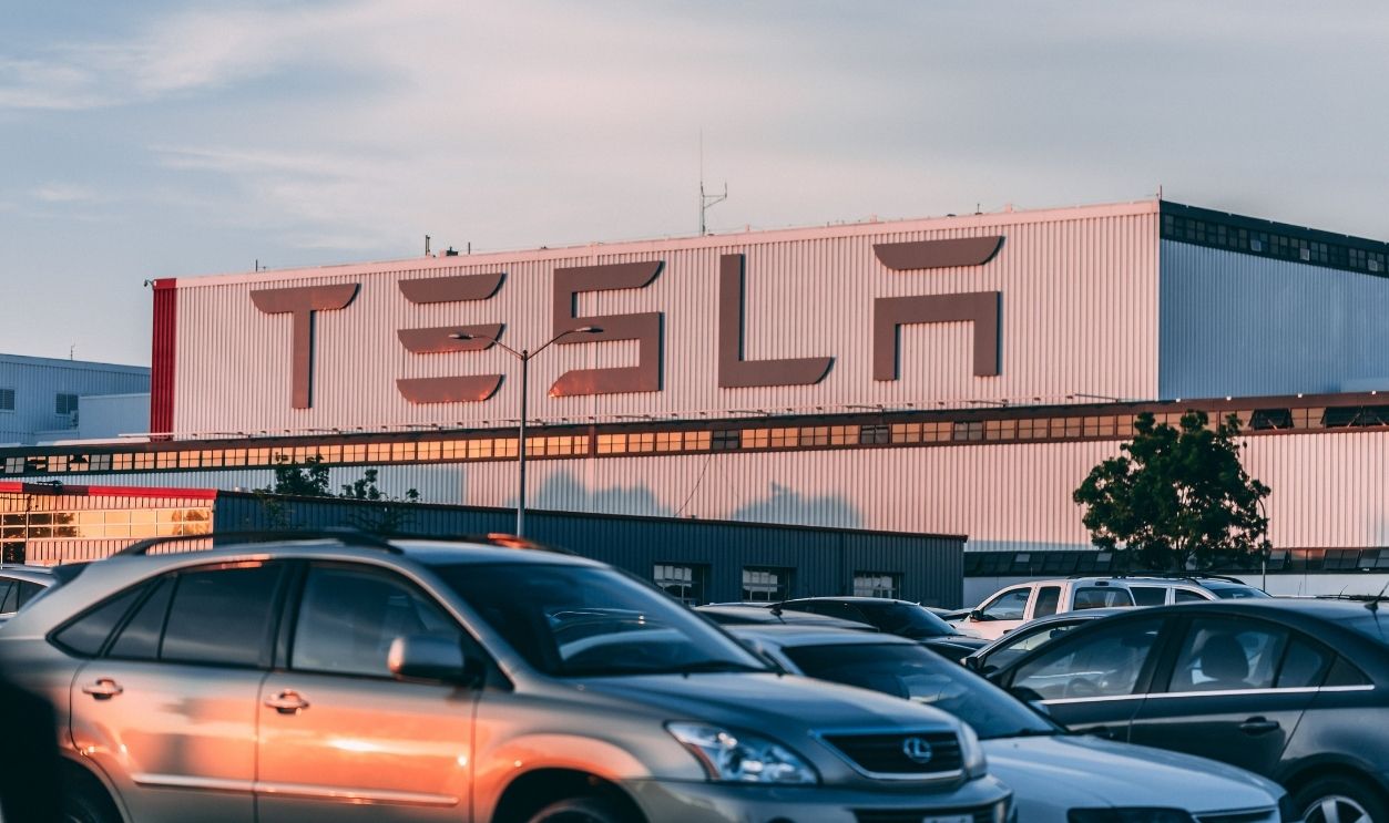 Tesla factory with parked cars during sunset, showcasing modern automotive