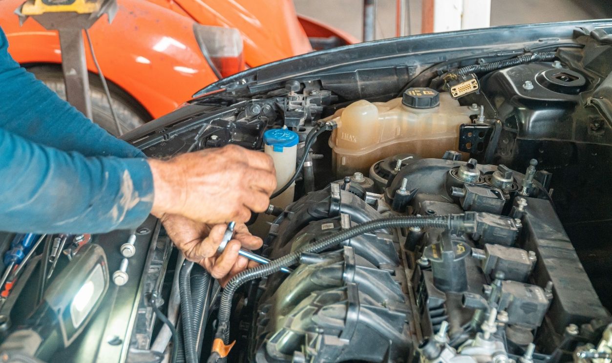 Mechanic's hands repairing a car engine, showing technical precision in an automotive garage.