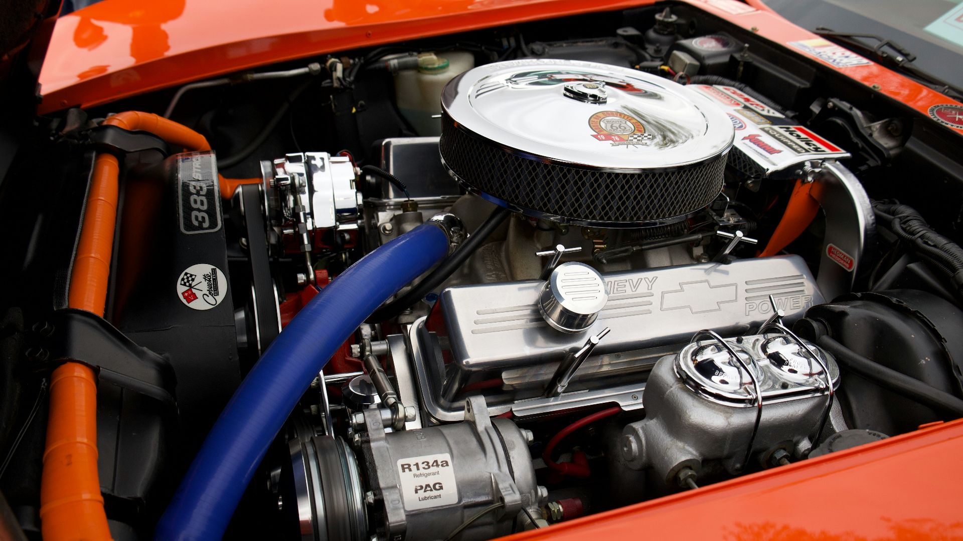 Bright orange car engine with chrome and blue accents.