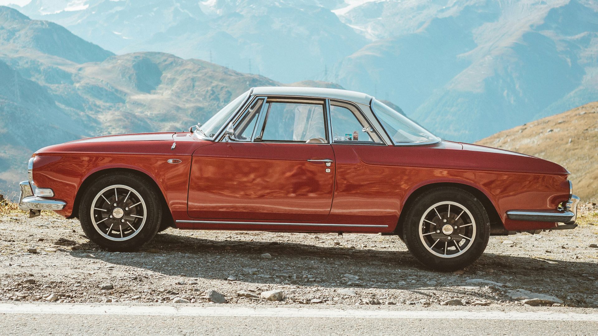 red sedan on gray sand during daytime