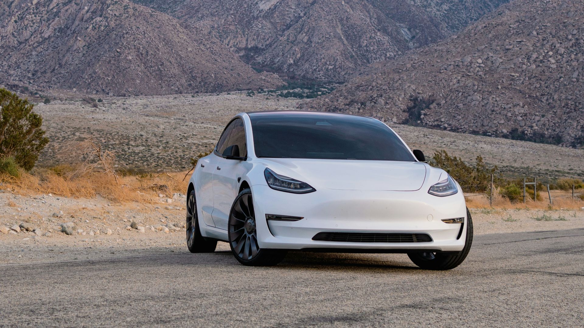 a white car parked in front of a mountain range
