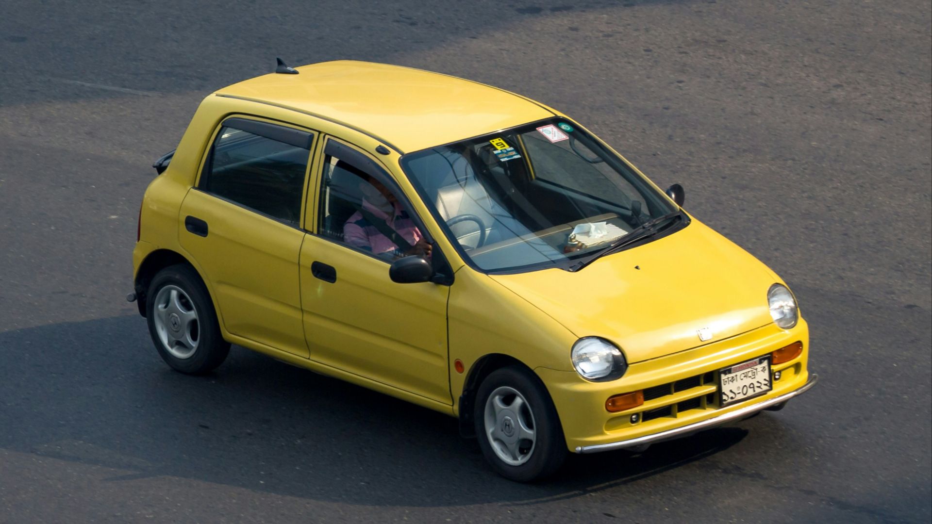 A yellow car driving on a road