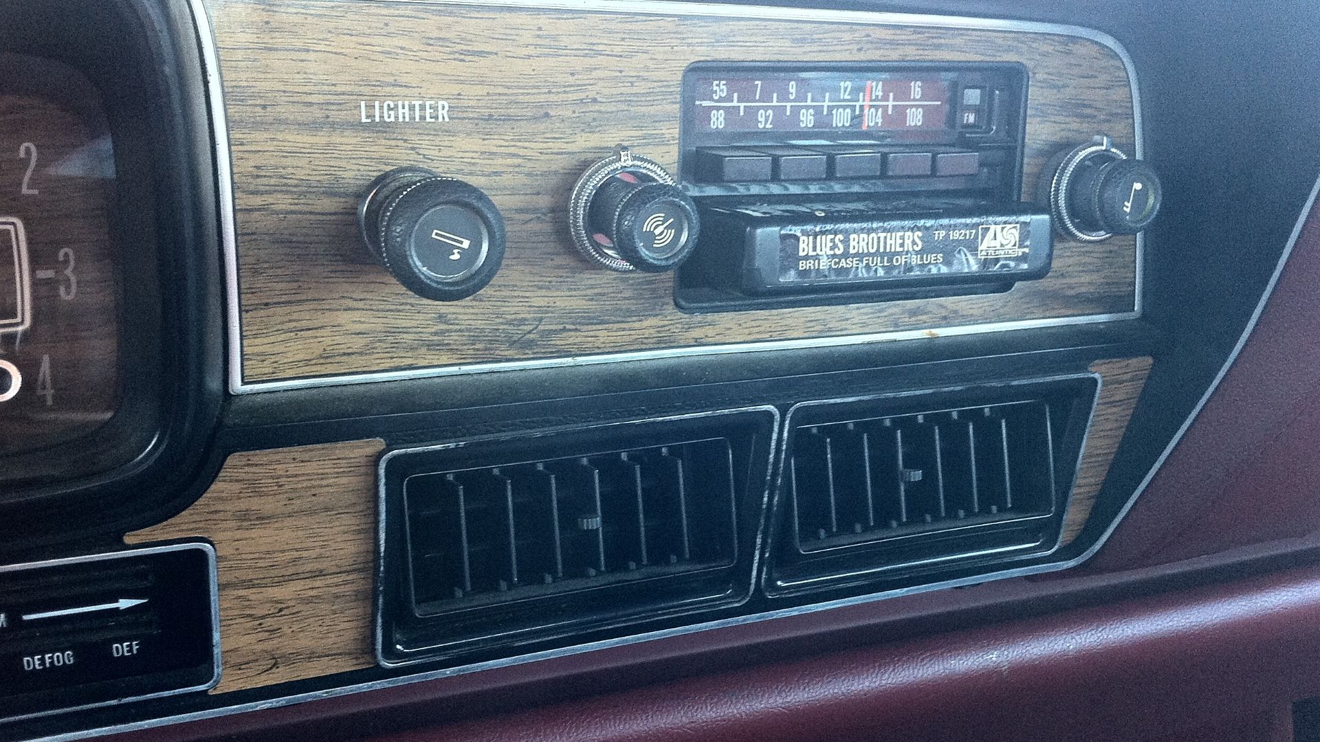 Detail of the factory installed AM/FM/8-track stereo audio unit in the instrument panel of a 1978 AMC Matador four-door sedan (made by American Motors Corporation). Also shown is the a tape cartridge in