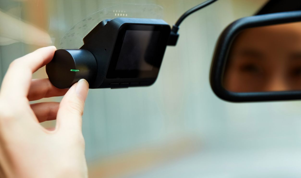 An Asian girl adjusts the dashcam inside the car.
