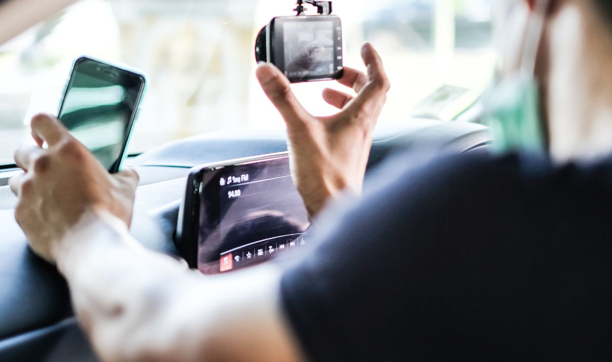 Close up Technician Hand with Car Camera and Smartphone Inside Car and Blur Man as a Foreground