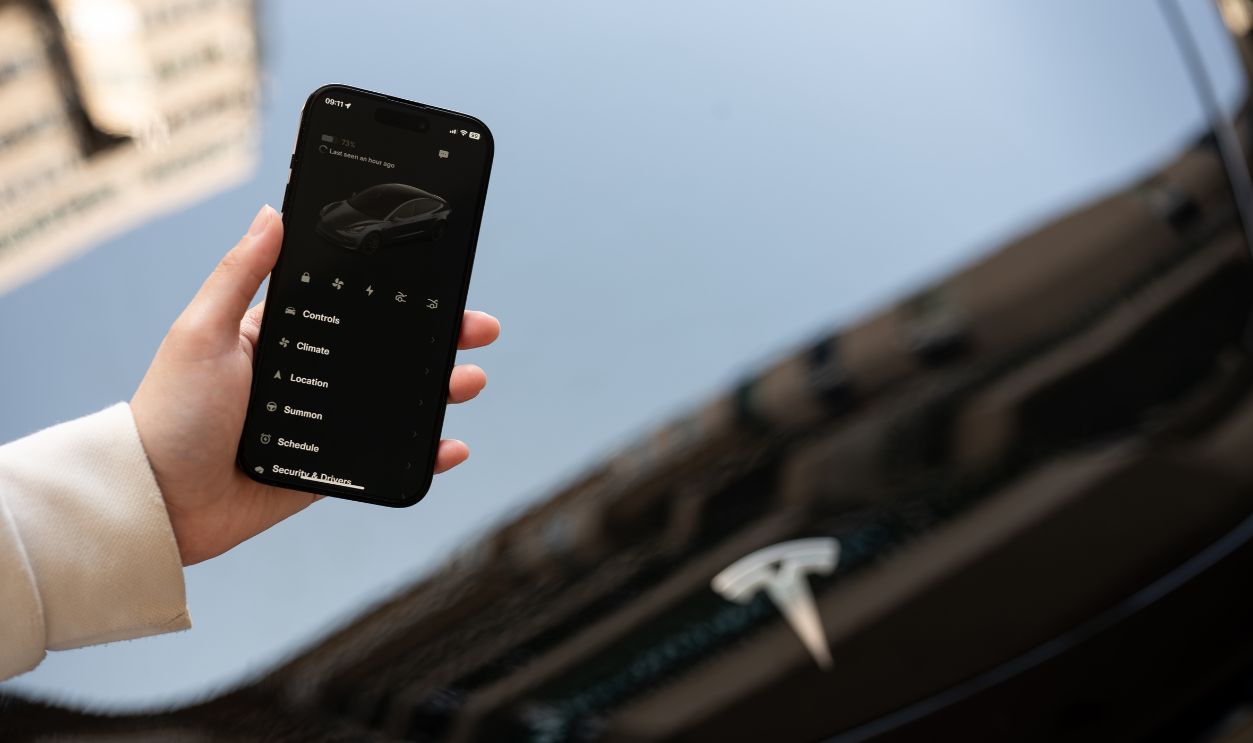 Chiang Mai, Thailand - Jan 08 2024: close-up image of a woman using the Tesla application on her iPhone14 outdoors.