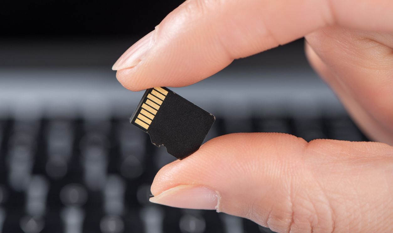 Hand holding sd memory card over laptop keyboard