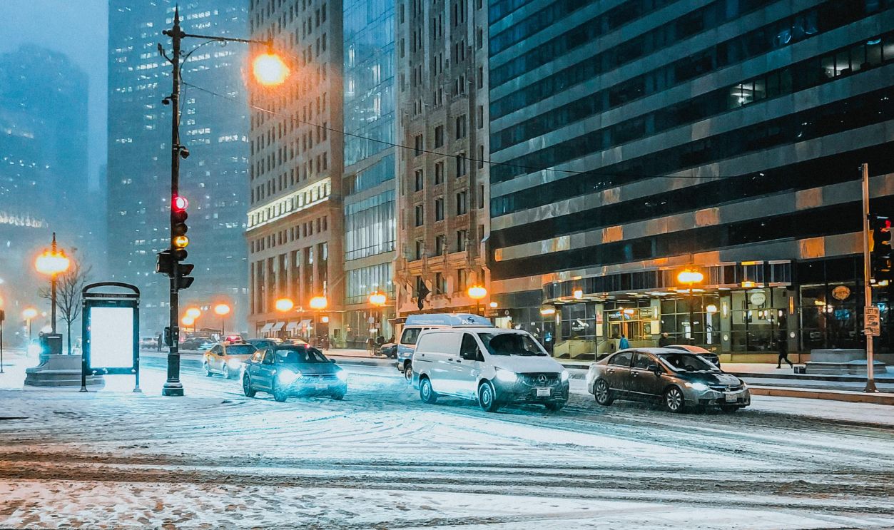 A snowy street scene in Chicago with towering skyscrapers and city lights at night