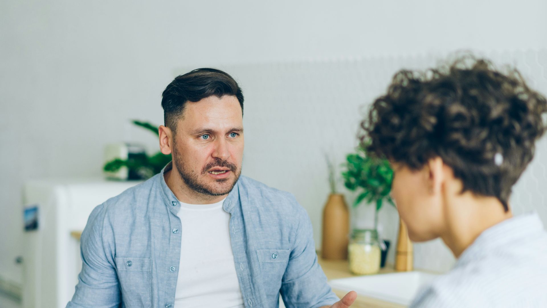 a man sitting at a table talking to a woman