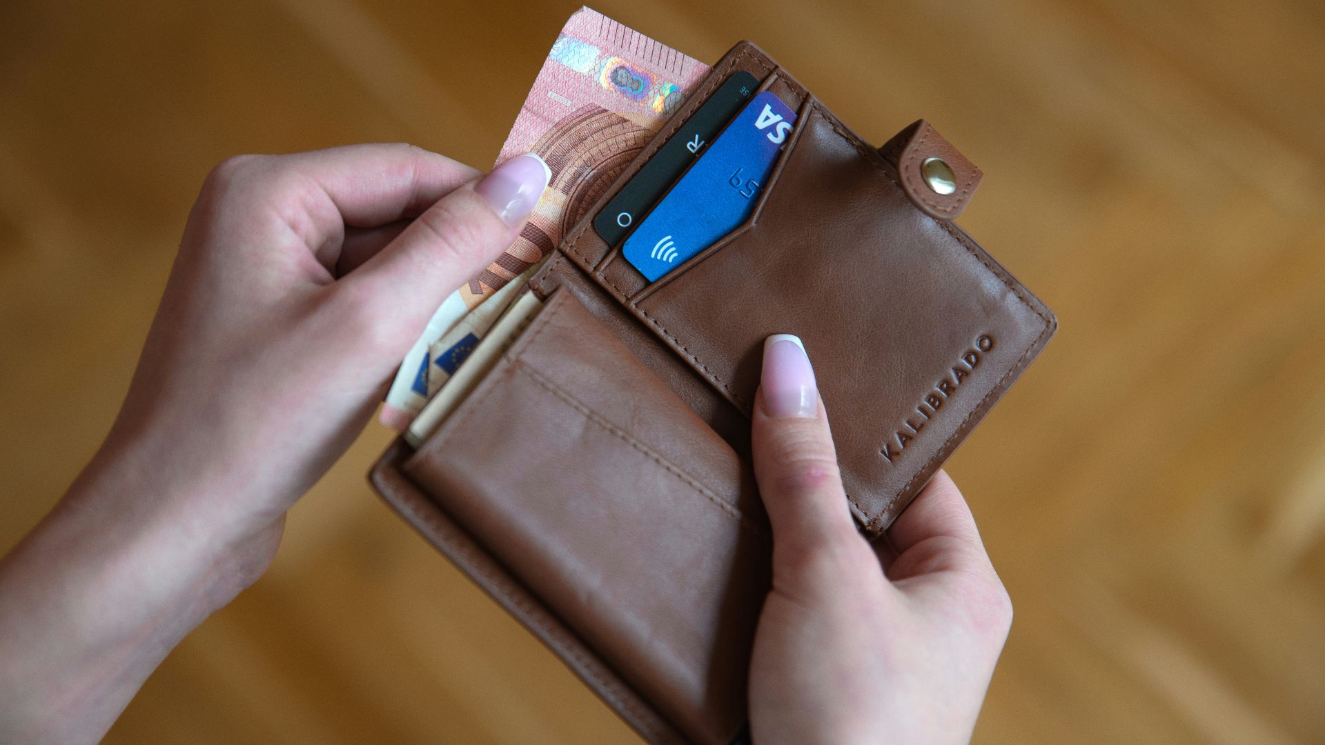 person holding brown leather card wallet
