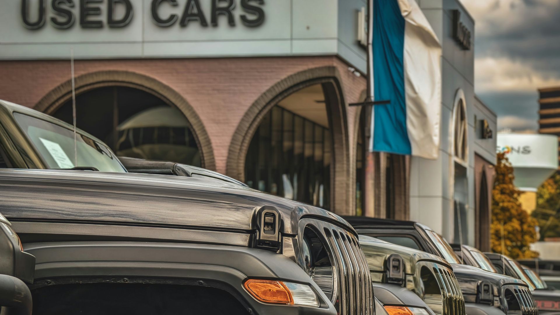 a row of parked cars in front of a used car store
