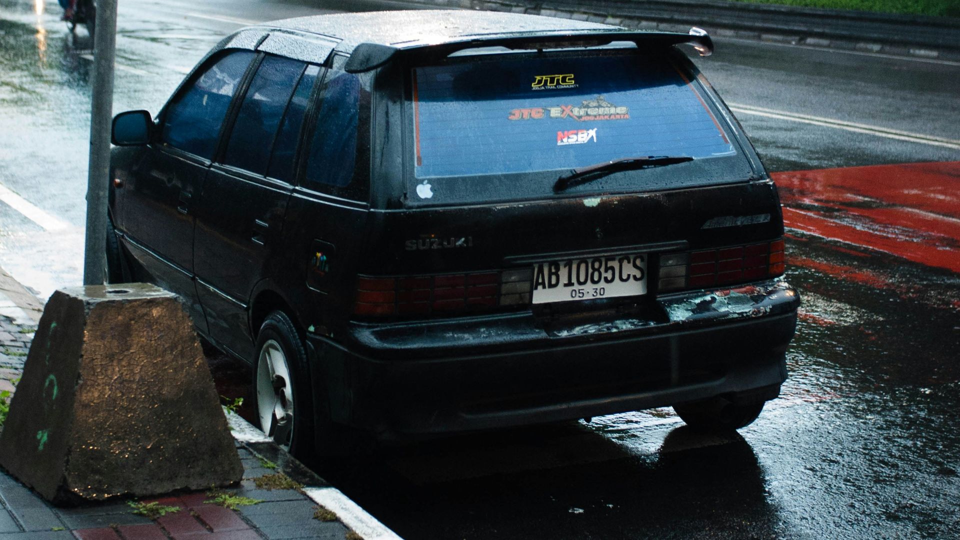 Black car parked on a wet city street.