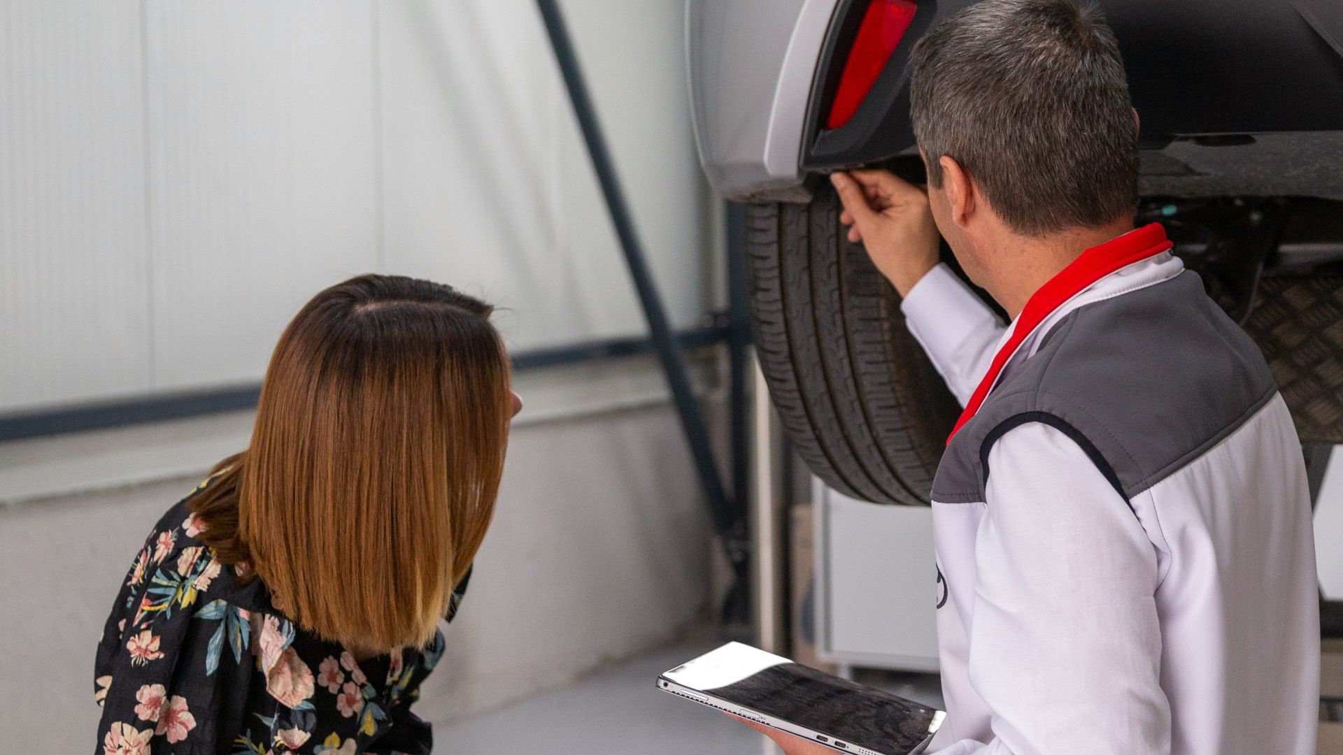 A man and a woman looking under a car