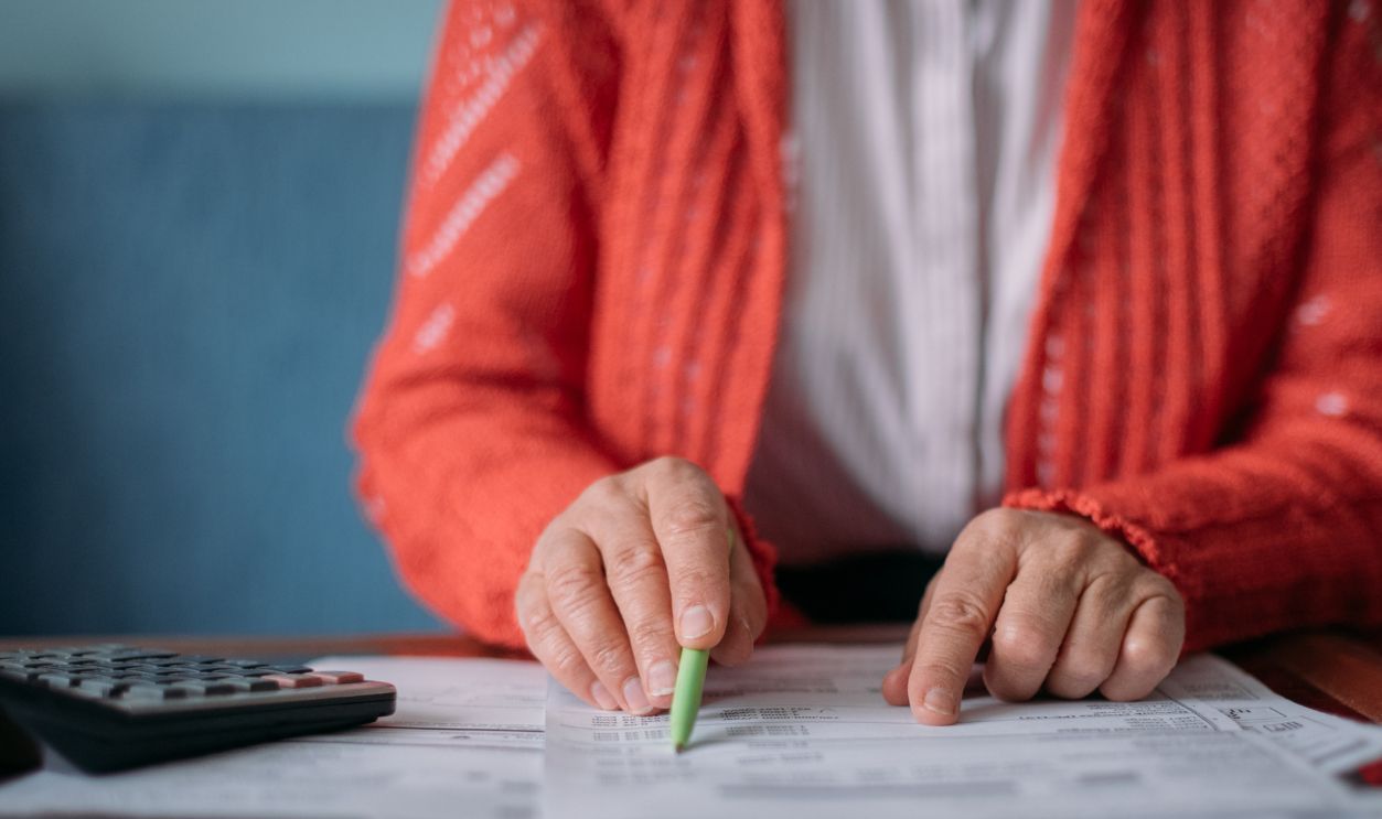 Shutterstock-2216940413, The hands of an elderly woman with a calculator and a lot of utility bills. Pensioner and payment of utilities for heating, electricity, gas