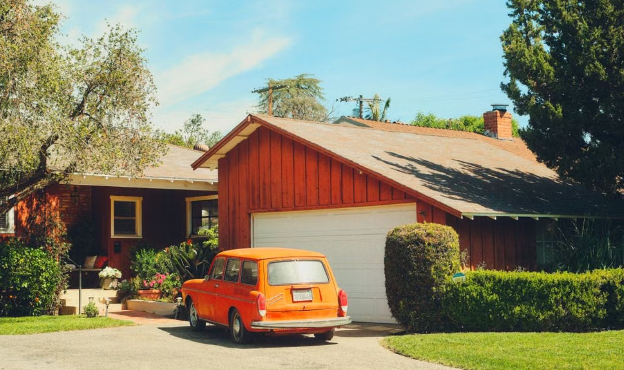 Classic orange car parked in a suburban driveway surrounded by greenery in Los Angeles