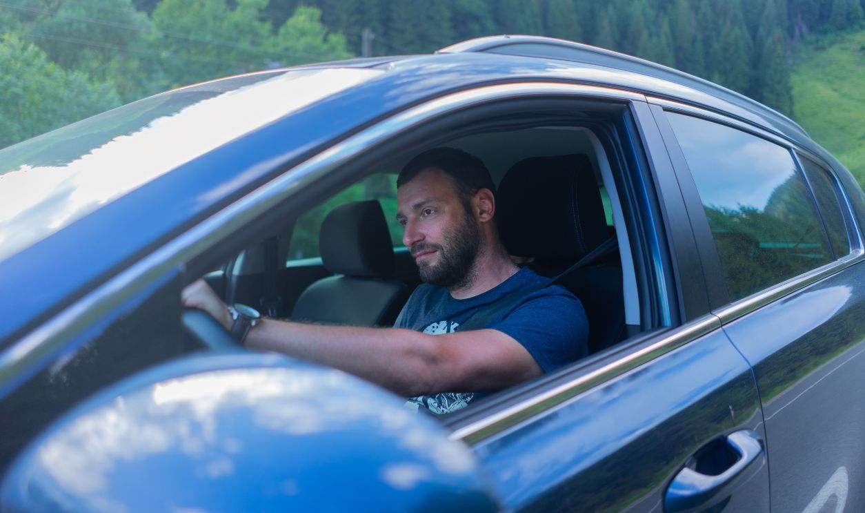 Bearded man enjoying a drive through lush green countryside