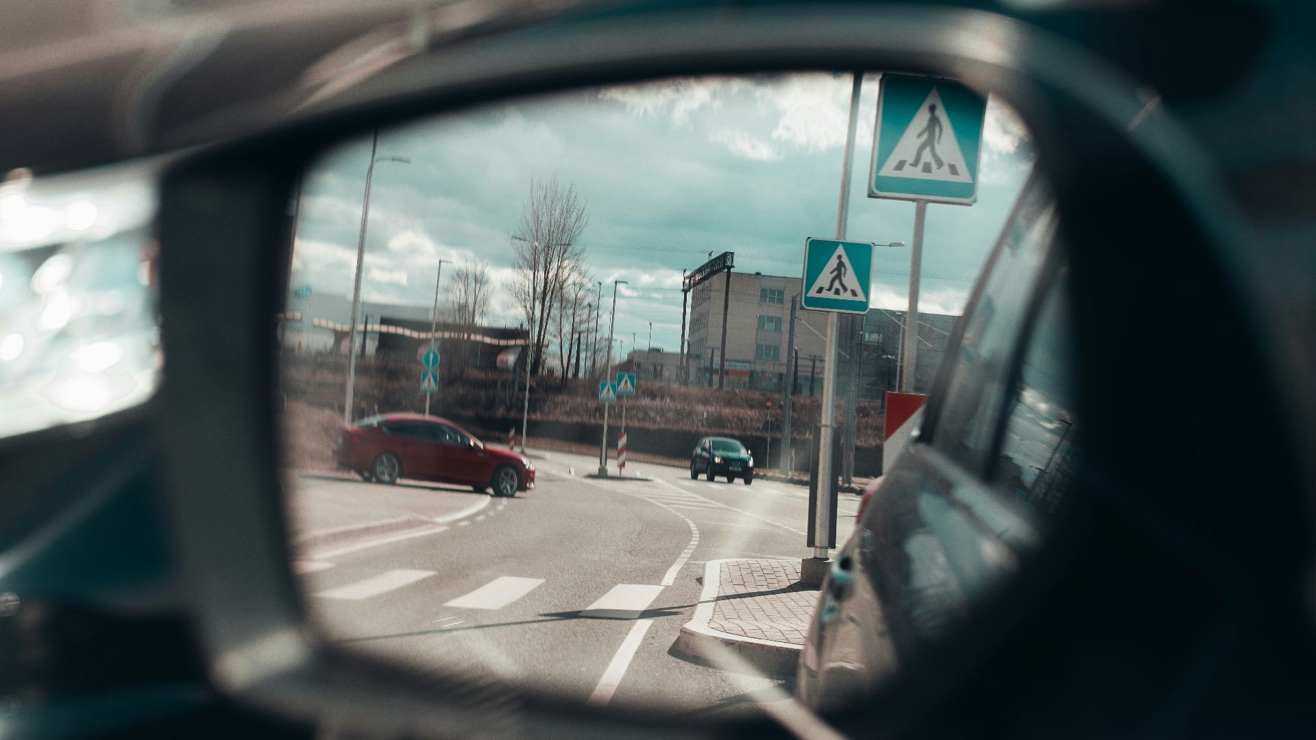 vehicle side mirror viewing red vehicle on road