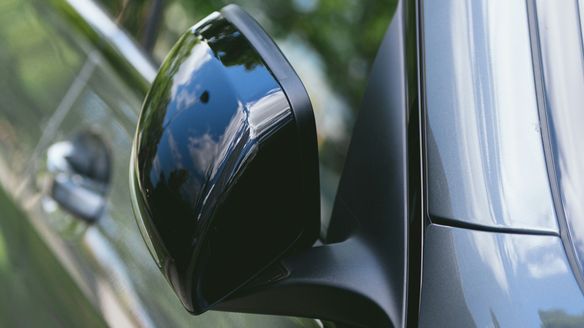 Close-up of a car's side mirror reflecting trees.