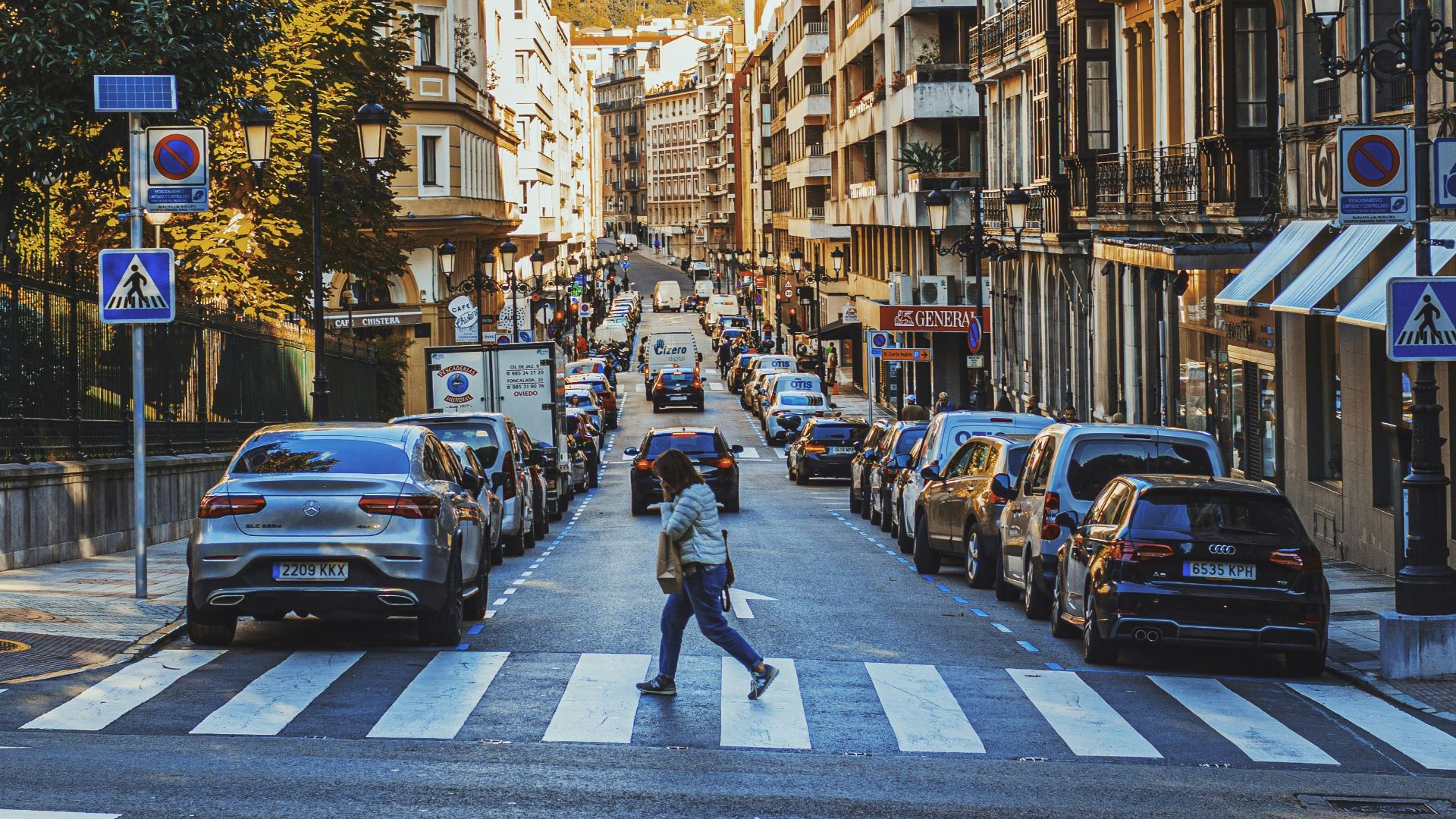 Person crosses street on a sunny day.