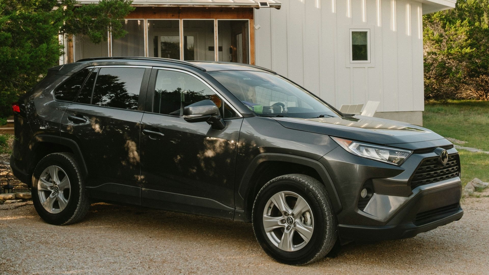 Dark suv parked outside a modern white house