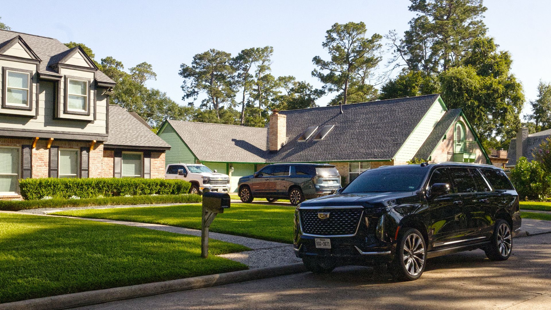 Black suv parked on a sunny suburban street with houses.