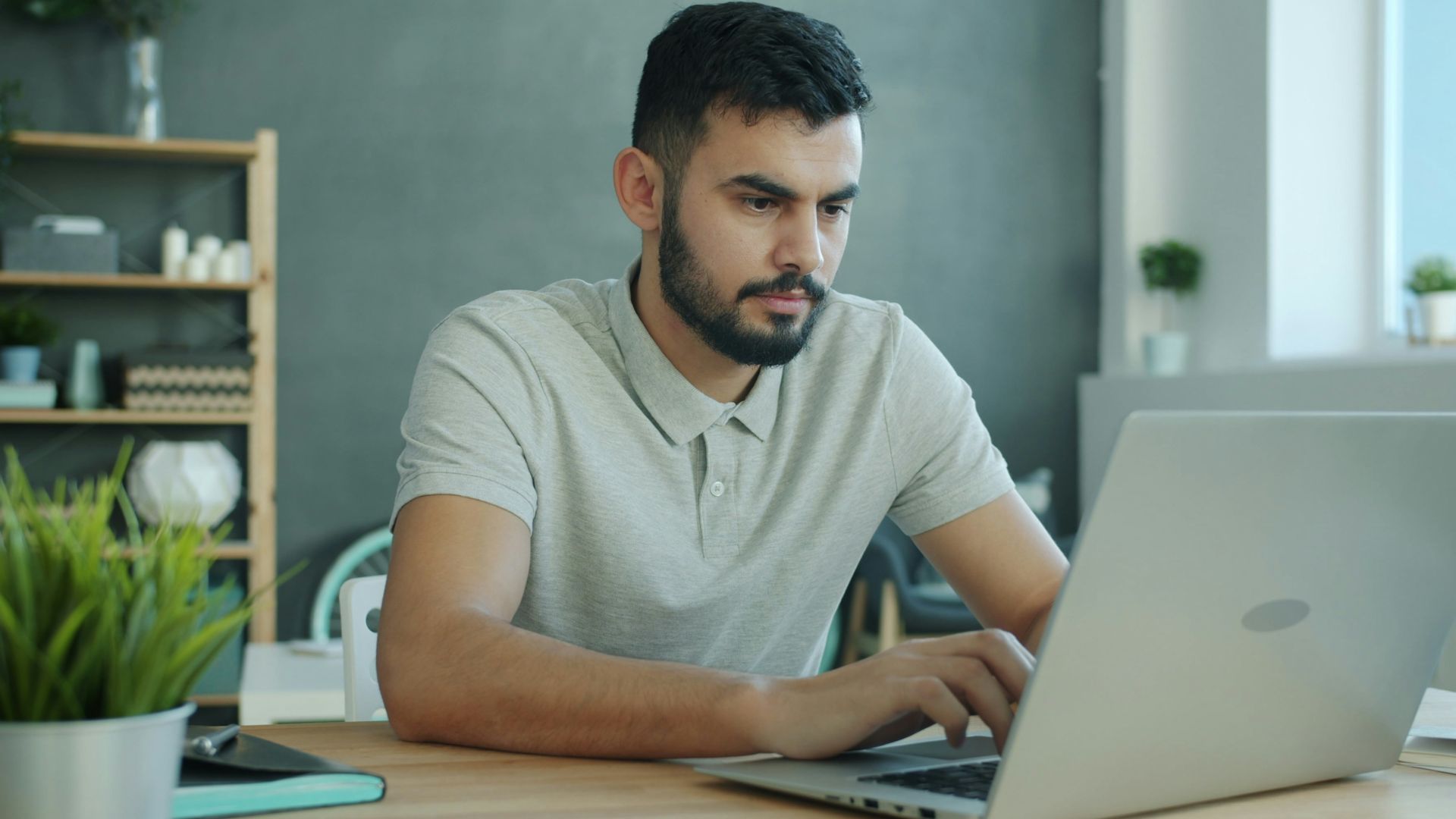 Man typing on a laptop at a desk.