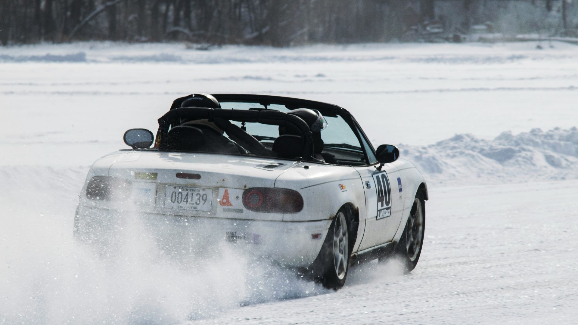 A white car driving through a snow covered field