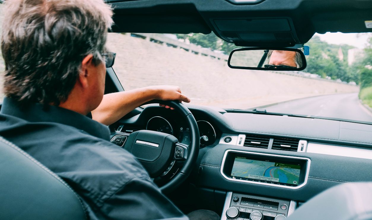 A man driving a convertible car on a scenic highway