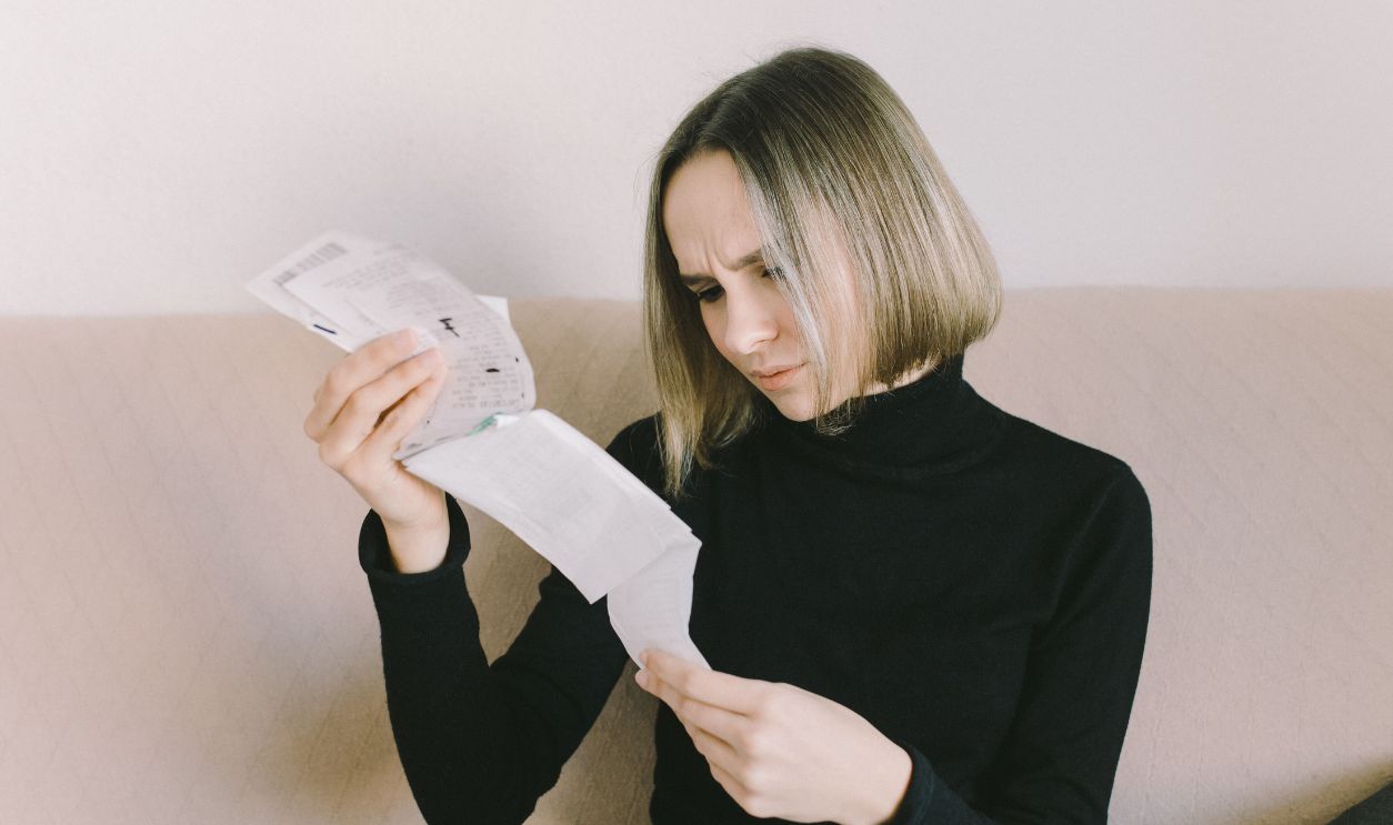 Concerned woman in black sweater examining receipts
