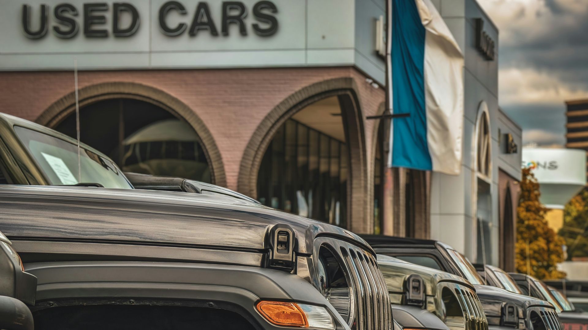 a row of parked cars in front of a used car store