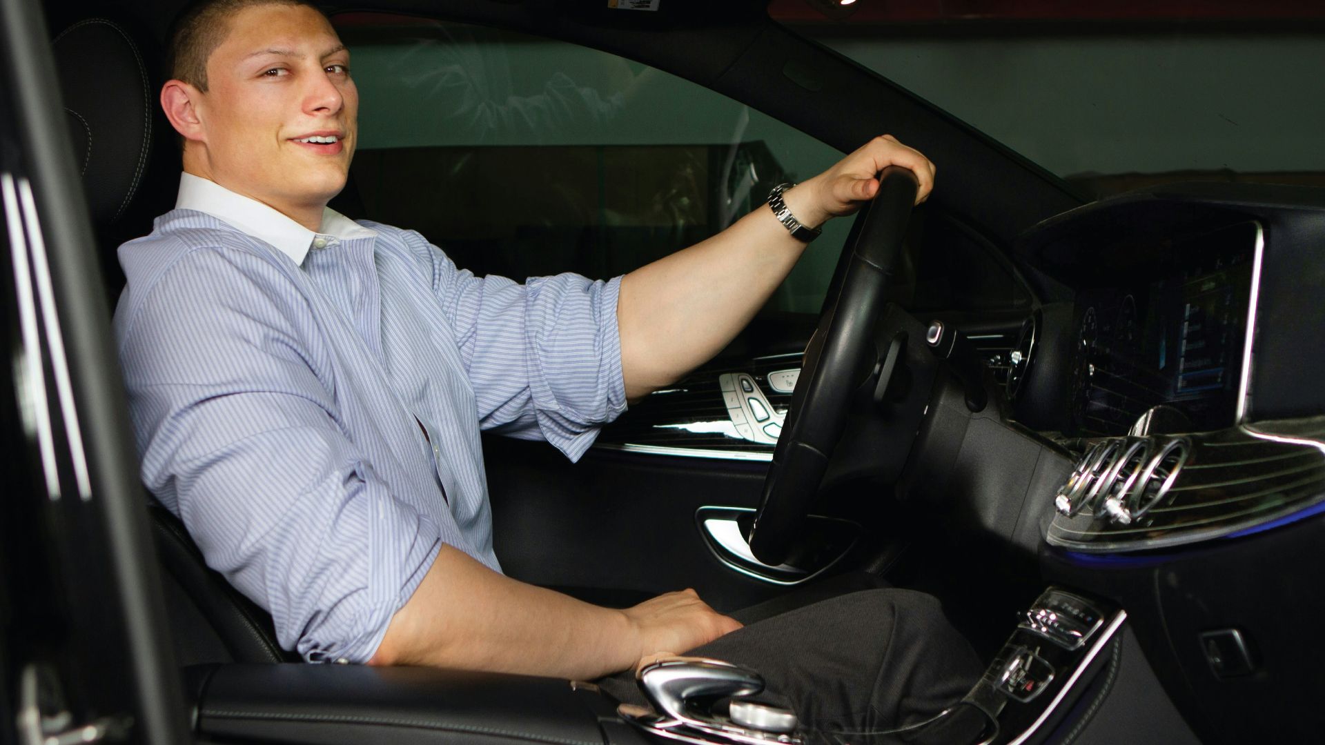 man in white and blue stripe dress shirt driving car