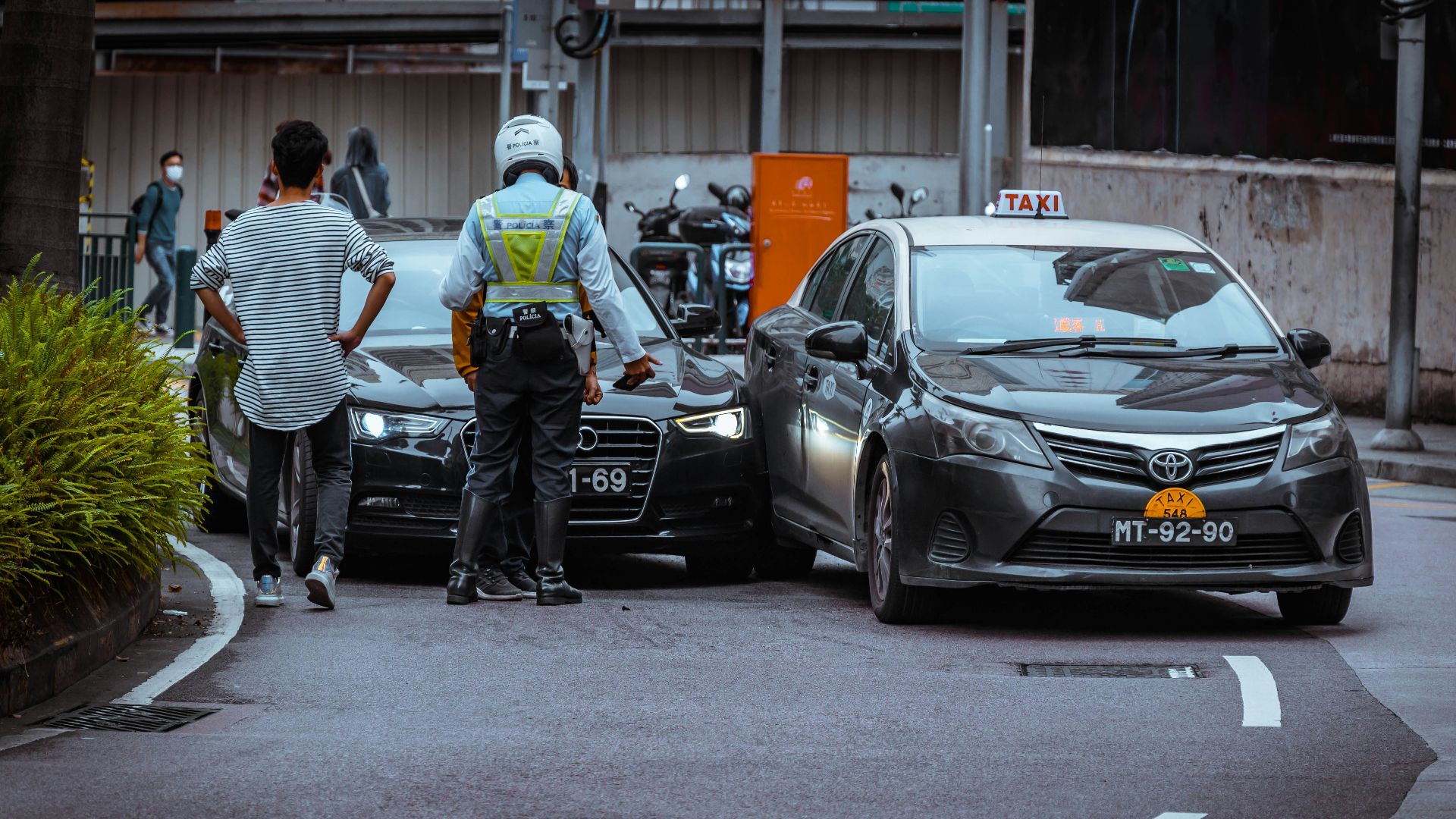 man in white and black stripe shirt and black pants standing beside black car during daytime