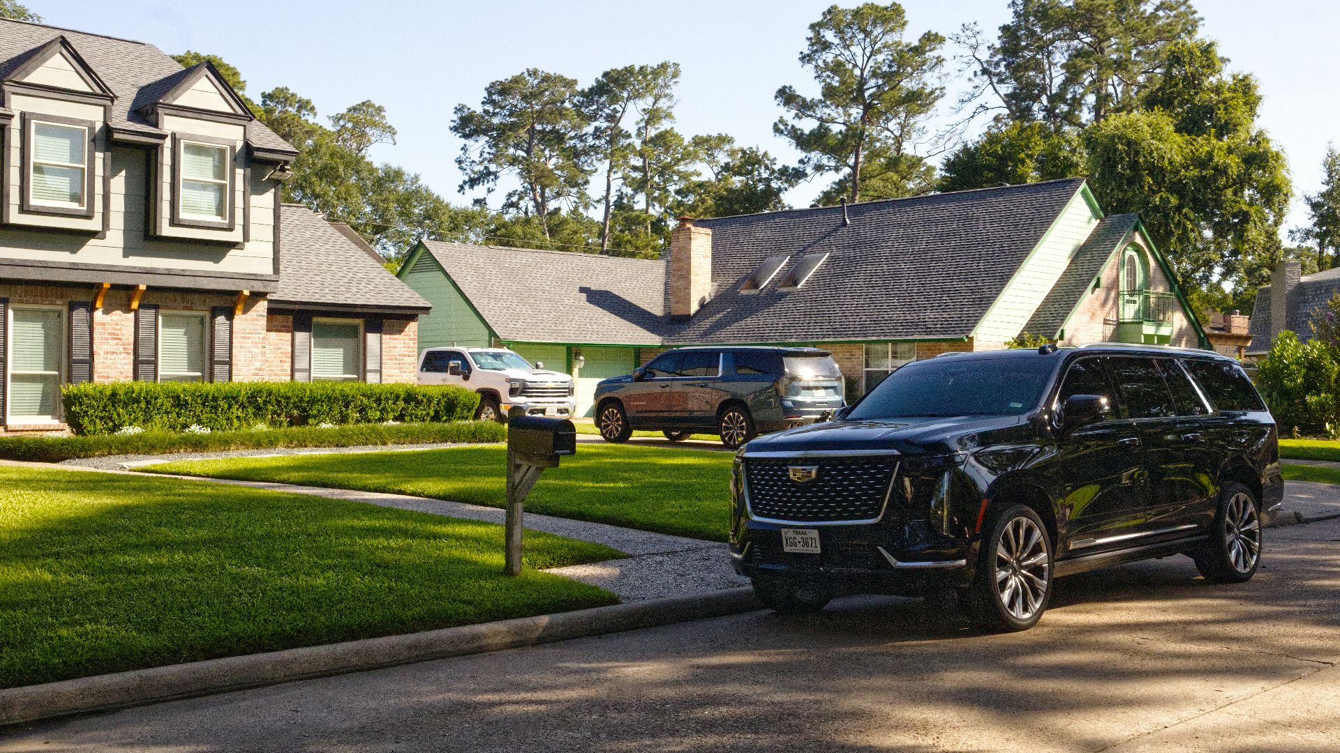 Black suv parked on a sunny suburban street with houses.