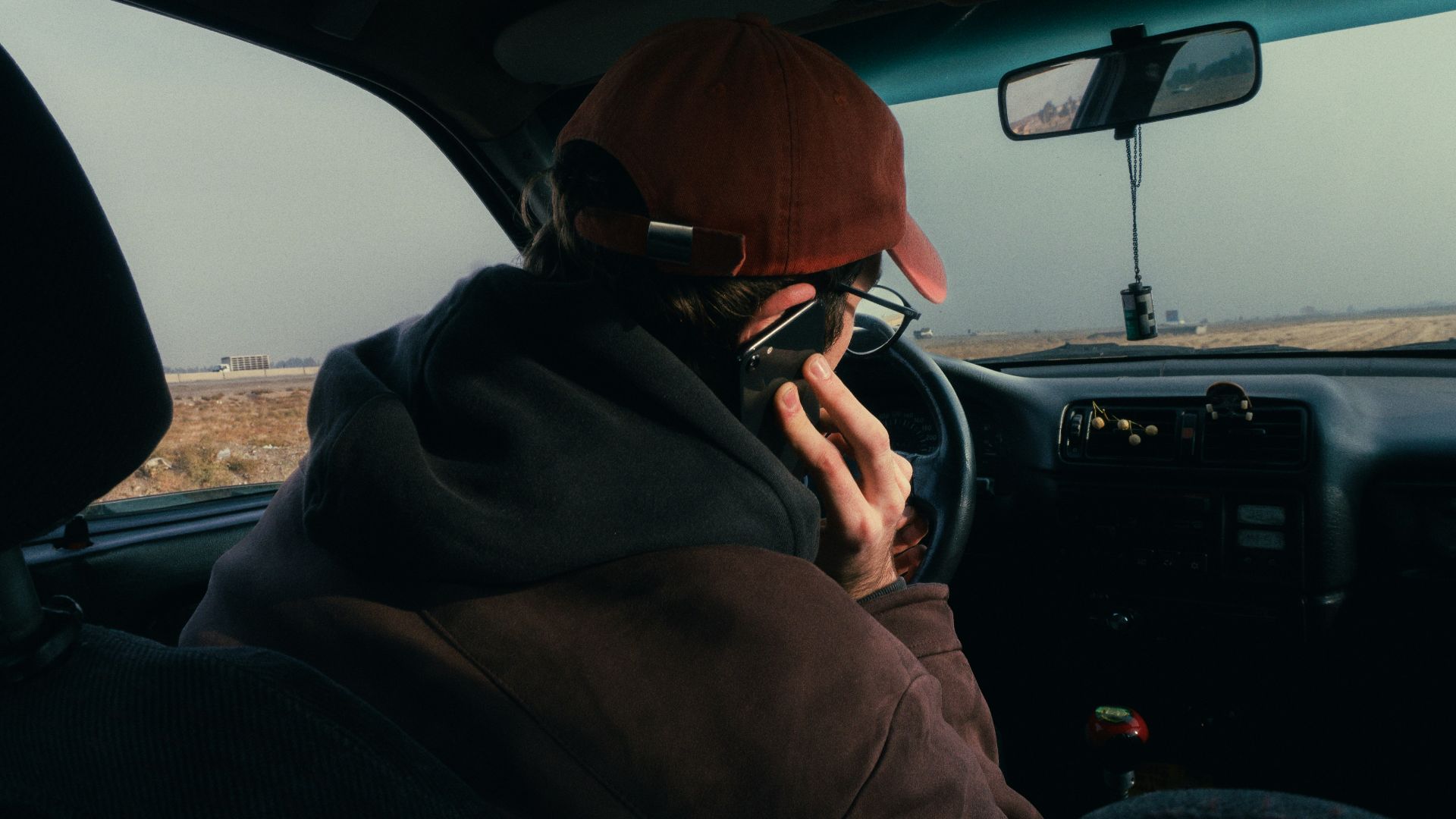 Person in car wearing a hat and glasses