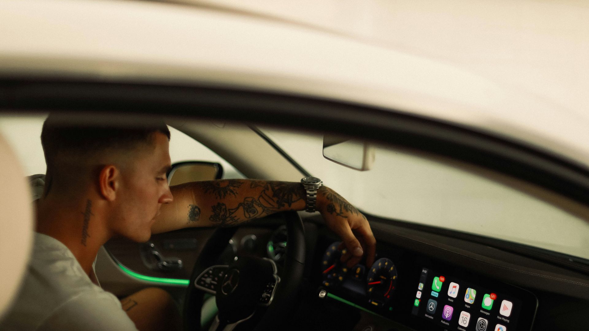 man in white polo shirt driving car