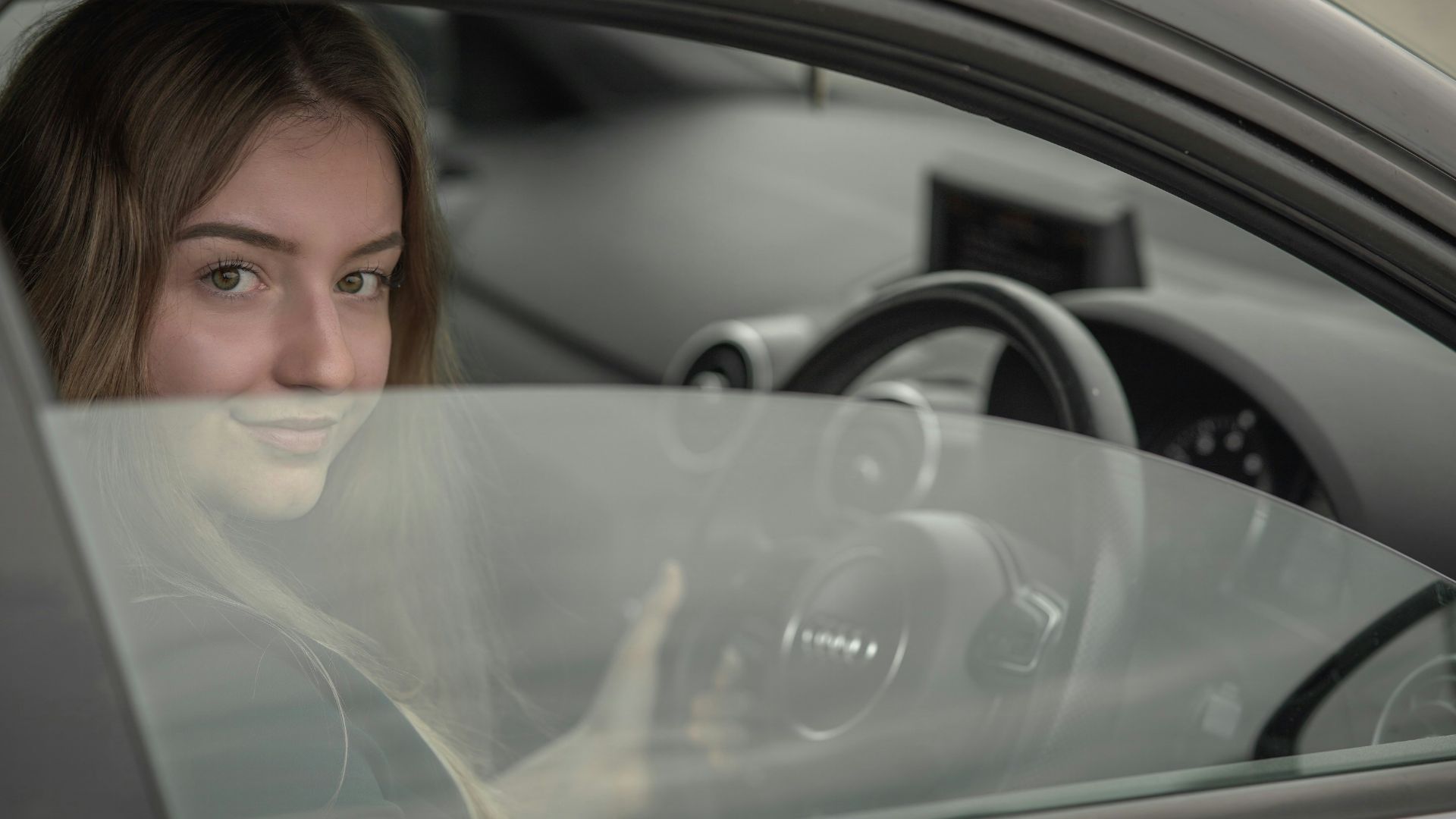 a woman sitting in a car holding a steering wheel