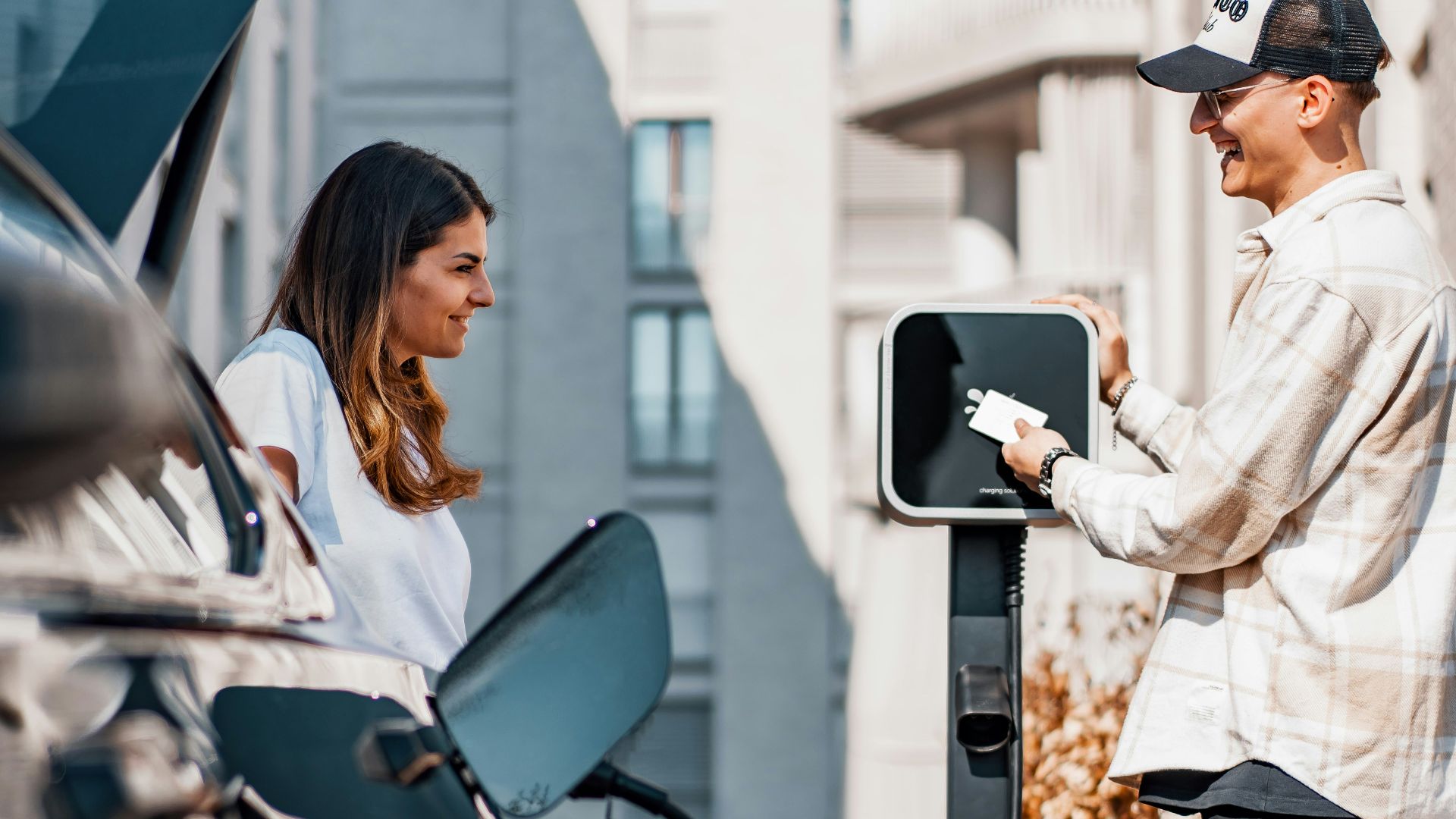 a man and a woman are charging their cars
