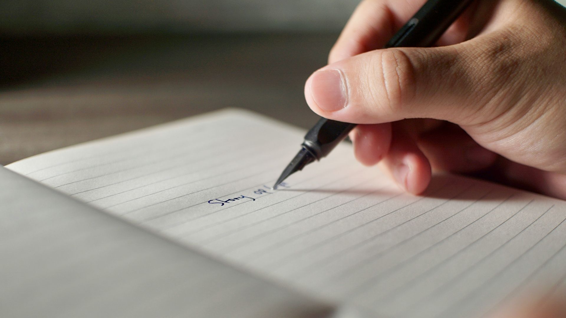 a person writing on a piece of paper with a pen