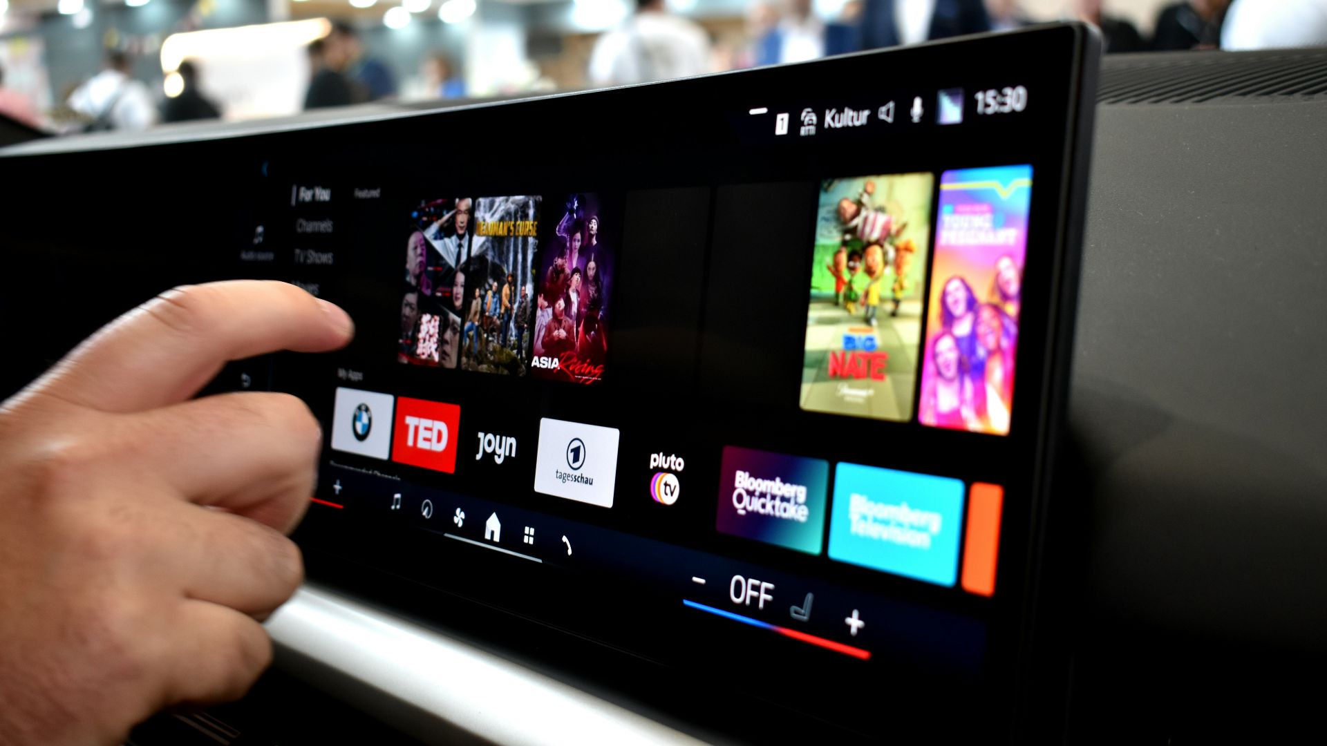 Person touching a car infotainment screen with media options