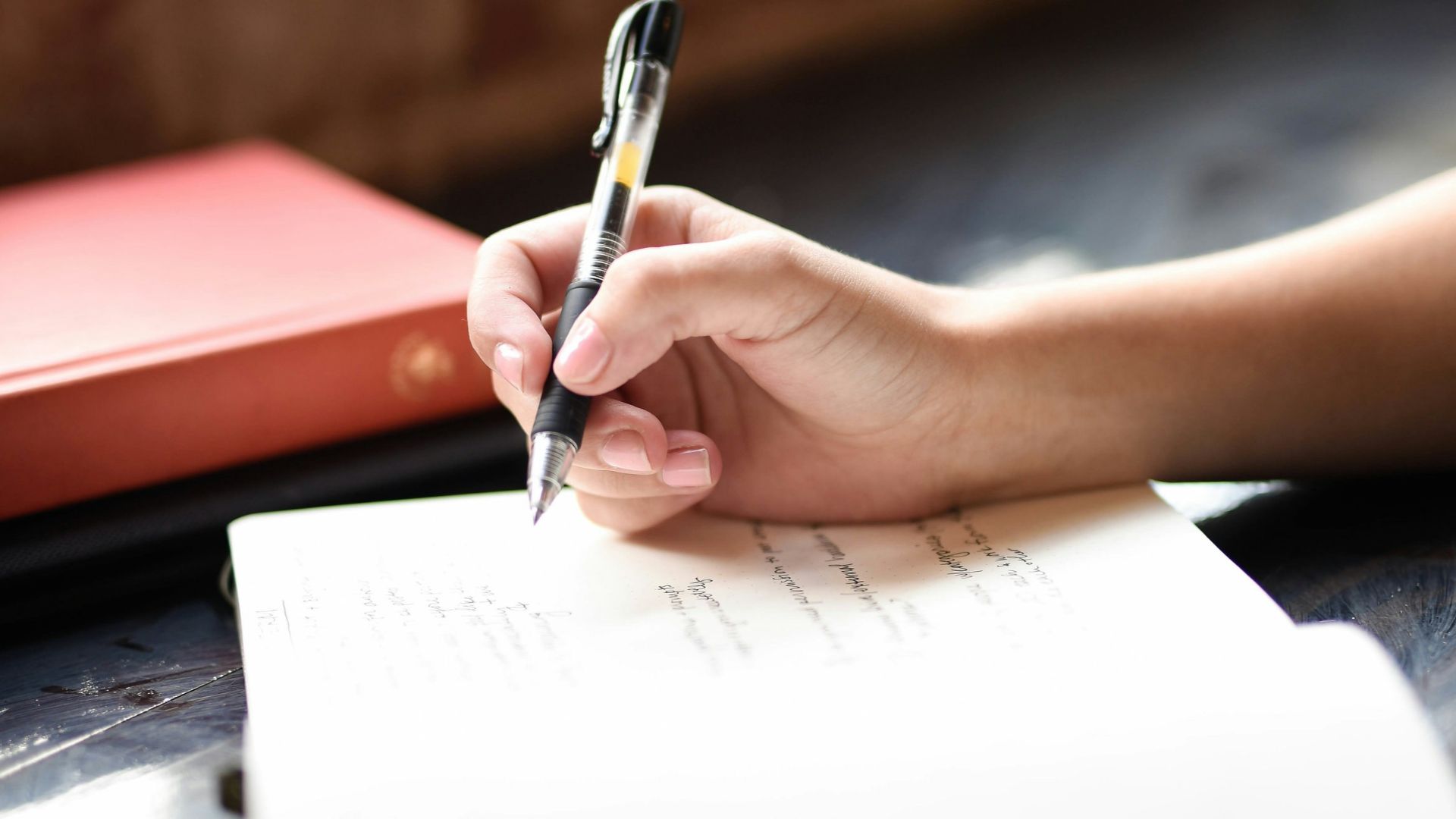 a person writing on a piece of paper with a pen