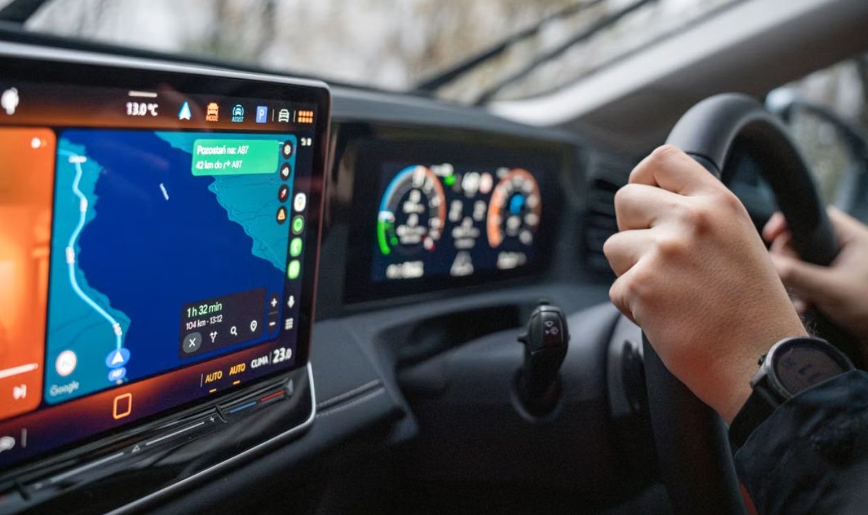 Close-up of hands on steering wheel and GPS navigation on car dashboard, showcasing modern driving technology
