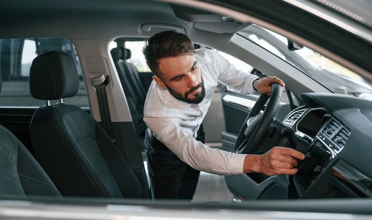 Shutterstock-2227097657, Examining the salon of the automobile. Young man in white clothes is in the car dealership.