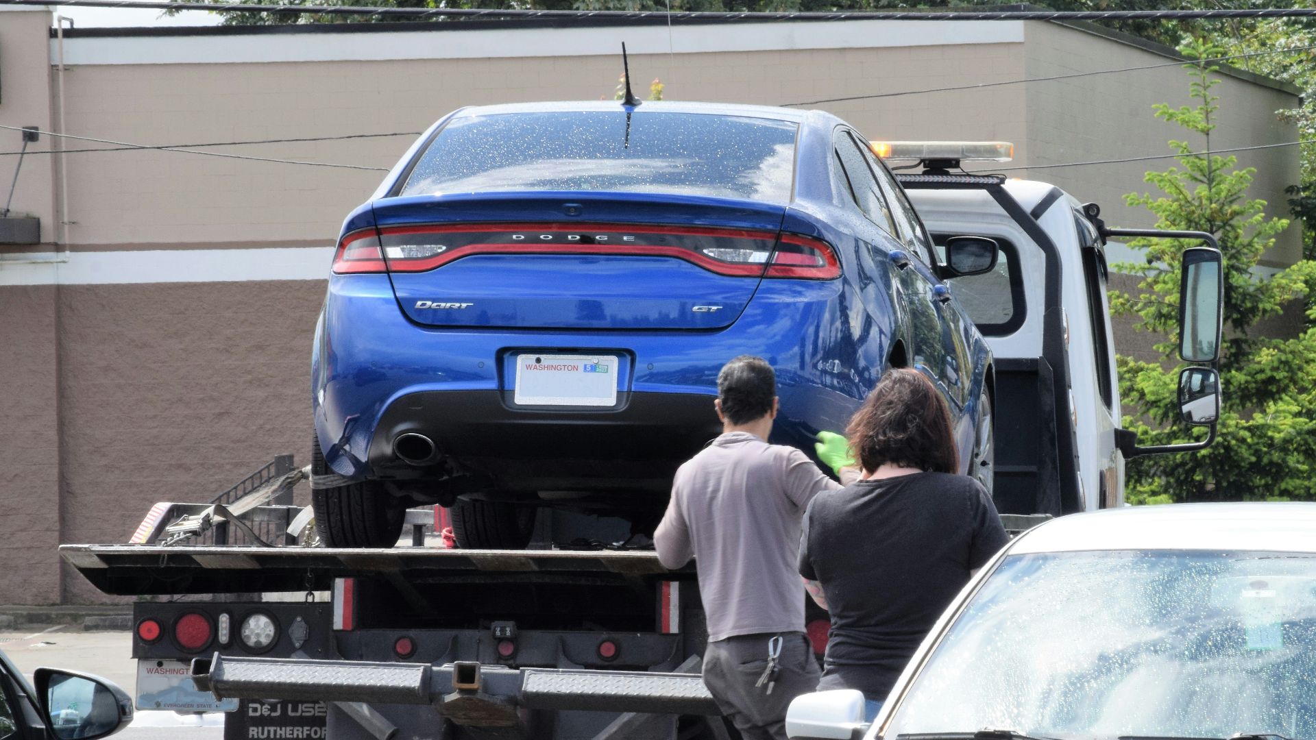 a blue car being loaded onto a flatbed truck